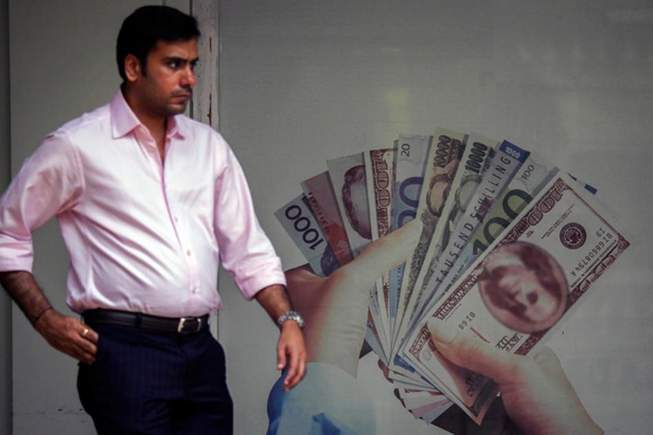 An  Indian  man  walks  past  an  advertisement  of  a  foreign  currency  exchange, in  Mumbai, India, 21 August  2013. EPA/DIVYAKANT  SOLANKI/FILE